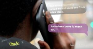 Super close up of a mobile phone up to an ear and pop up text messages on the image from a helpline