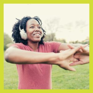 Young woman with earphones on stretching in nature
