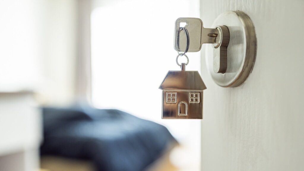 Key in open door with a house shaped keyring