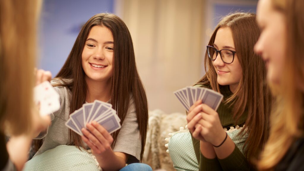 Four girls playing a card game holding the cards in front of them