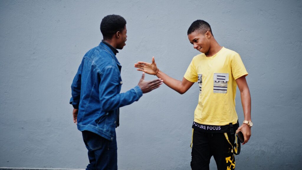 Two teen boys greeting each other with a handshake
