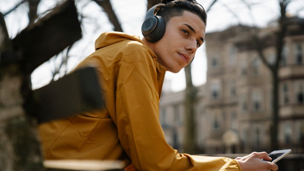 Teenage boy sat on bench with headphones on