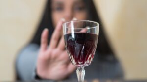 A woman refusing a glass of red wine