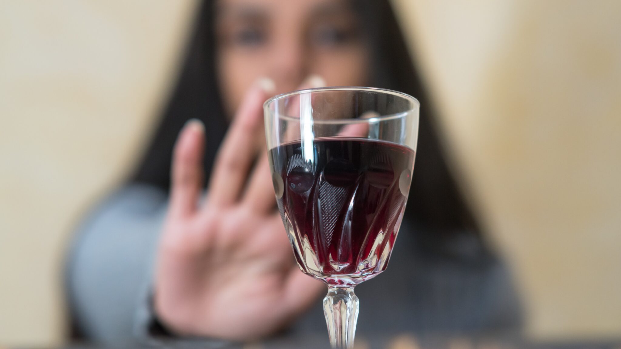 A woman refusing a glass of red wine