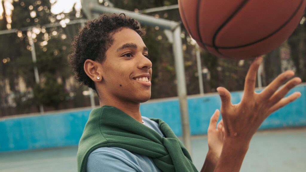 Young boy with his ears pieces balancing a basketball on his finger on a basketball court