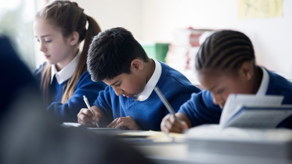 Three students working quietly at a table in a classroom