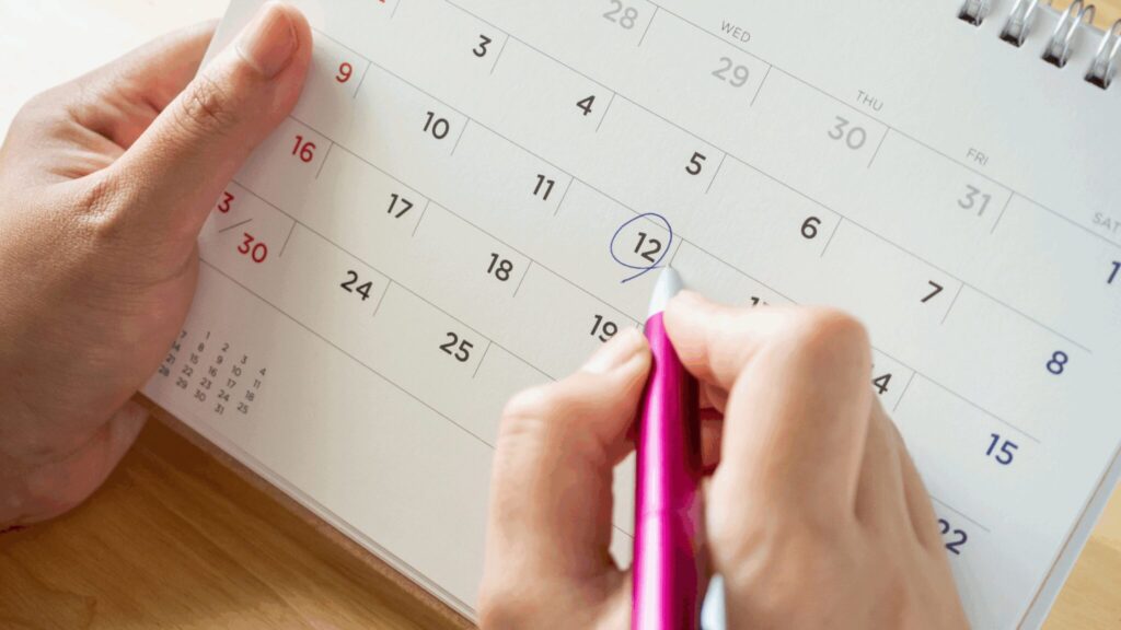 Person circling a date in the calendar with a pen