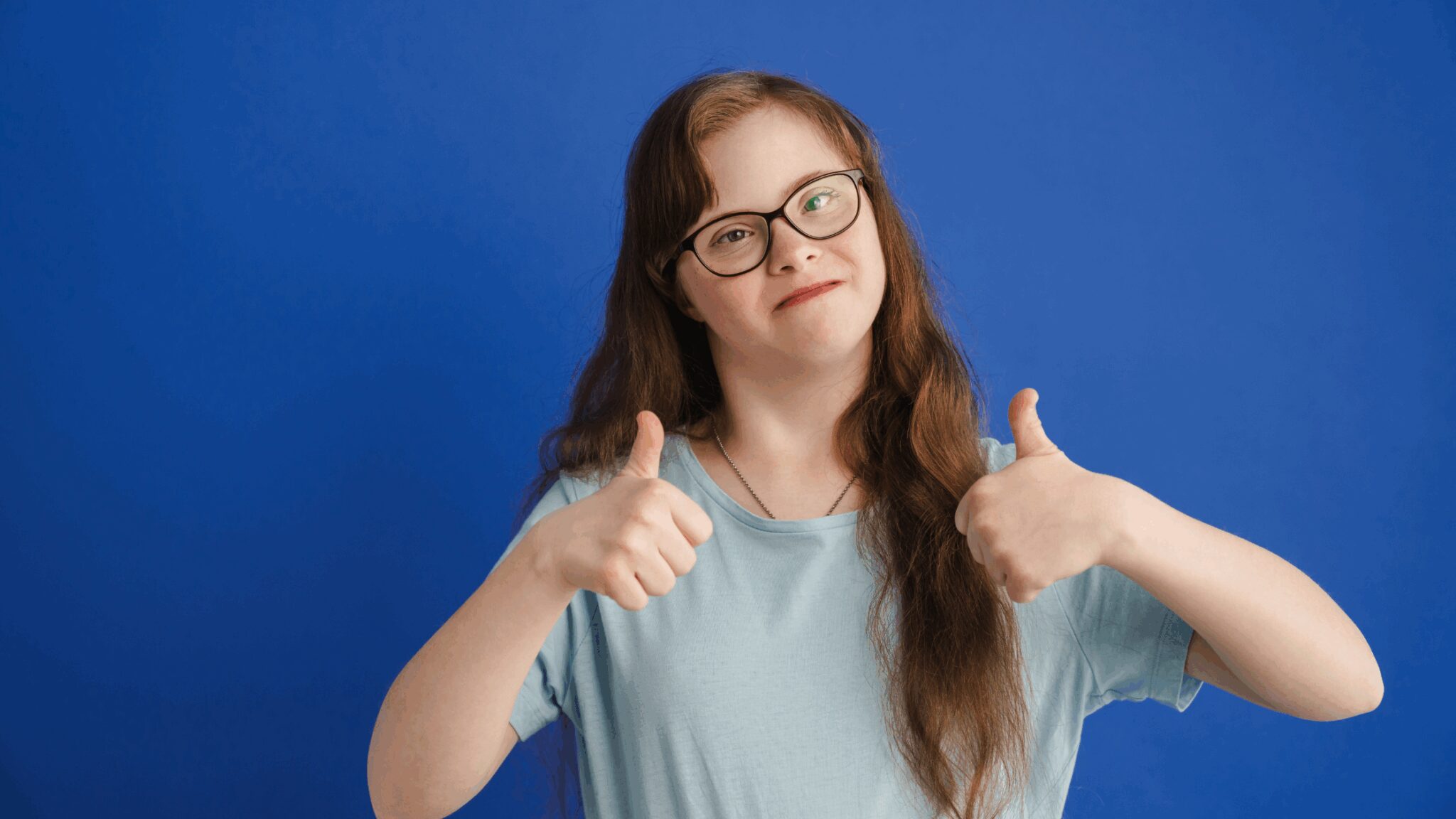 A picture of a young woman with Down syndrome giving a thumbs up