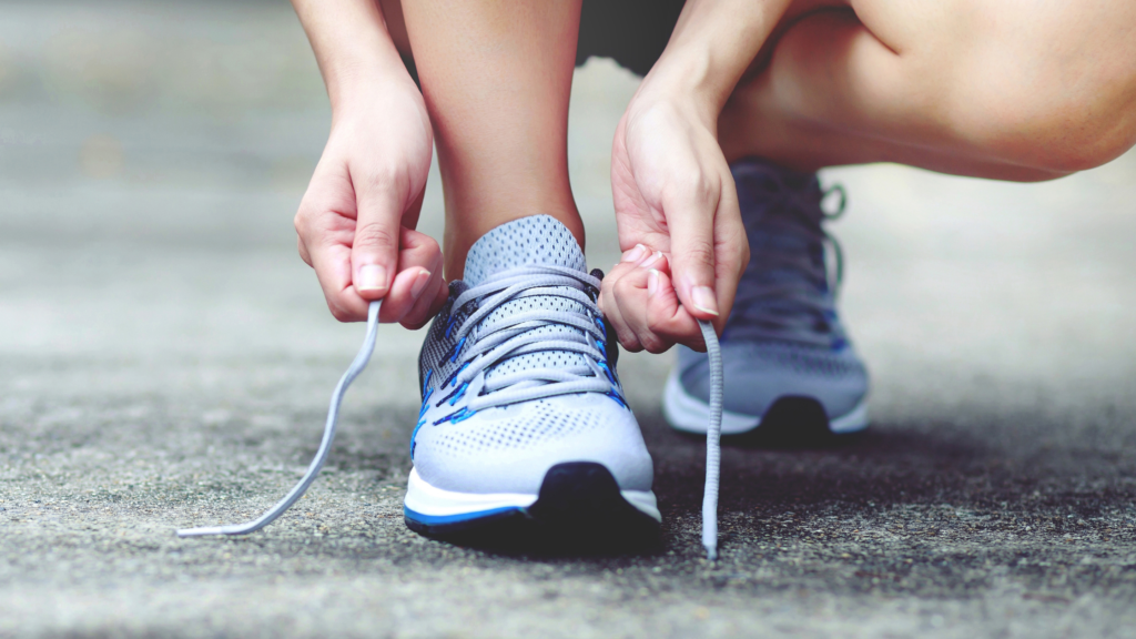 Lady tying the laces of blue trainers