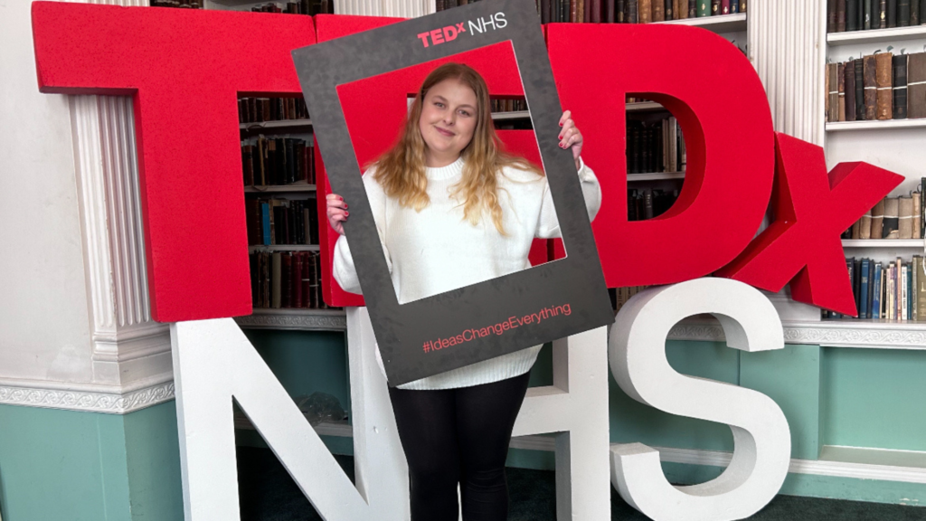 Molly Fenton standing in front of a of TEDx NHS