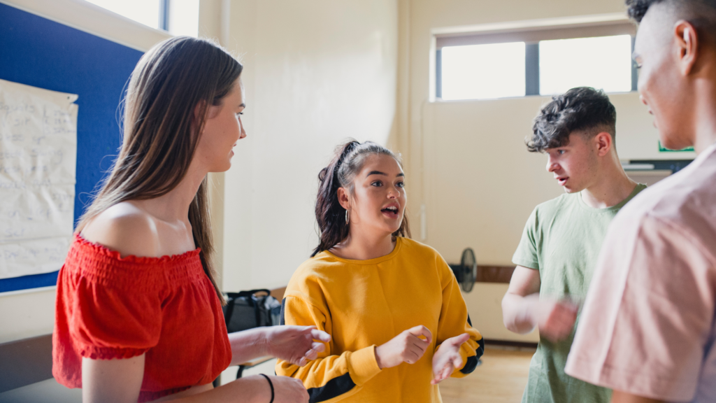 Four young people smiling and talking in an open room.
University life