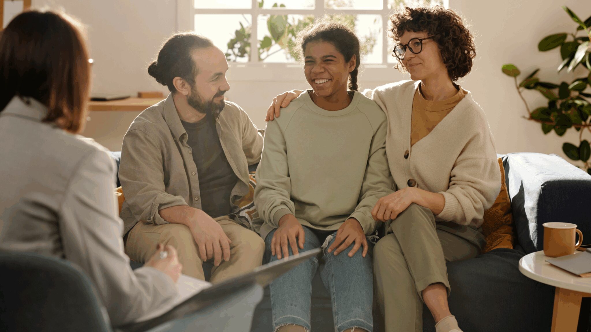 Teen girl in care sitting with foster family on sofa
