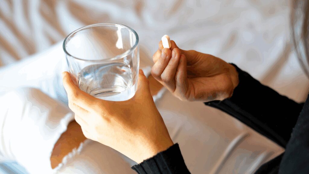 Person holding a cup of water and a tablet