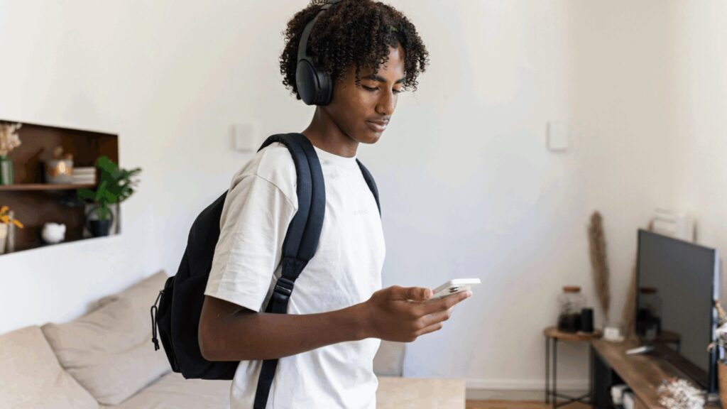 Young man texting on his mobile phone which wearing headphones