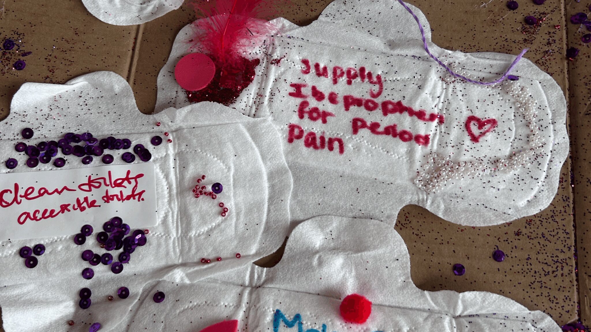 Period pads decorated with campaigning slogans, such as 'supply ibuprofen for period pain'