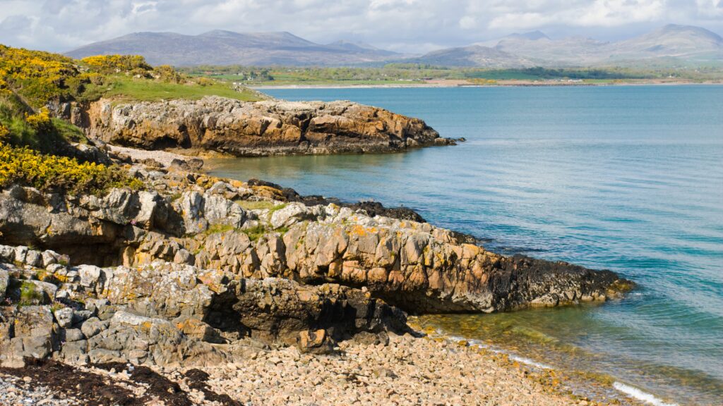Rocky cliffs on beach, meeting with bright blue water