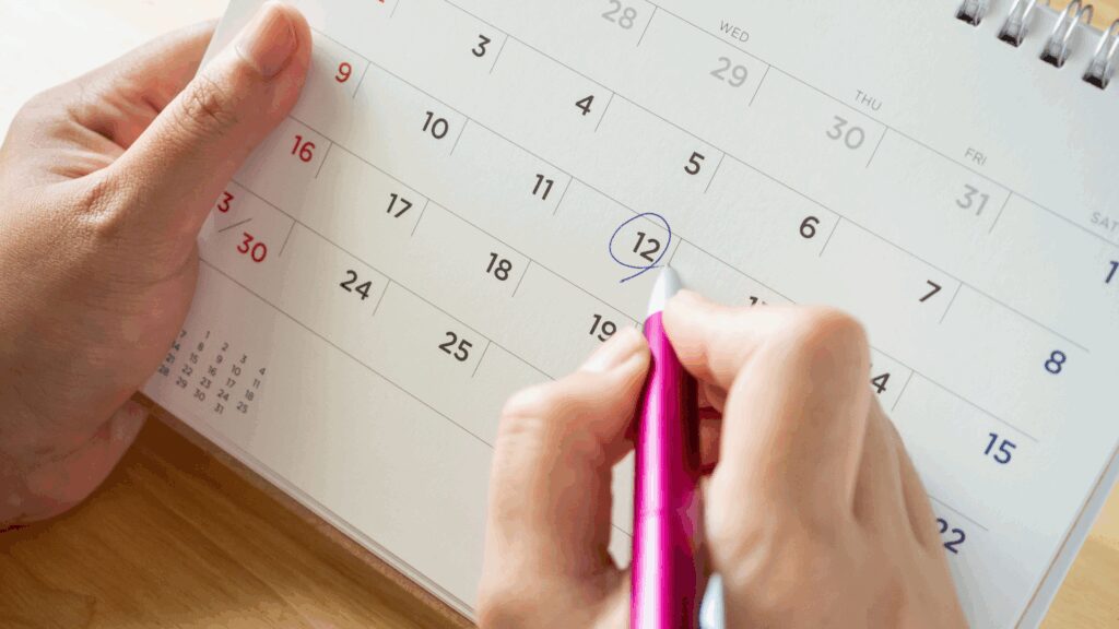 Person circling a date in the calendar with a pen