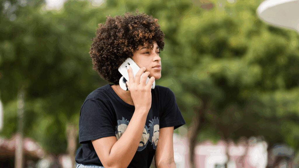 Person sat outside calling on a mobile phone. Mental health strategy